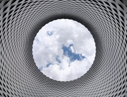 low angle photography of grey and black tunnel overlooking white cloudy and blue sky