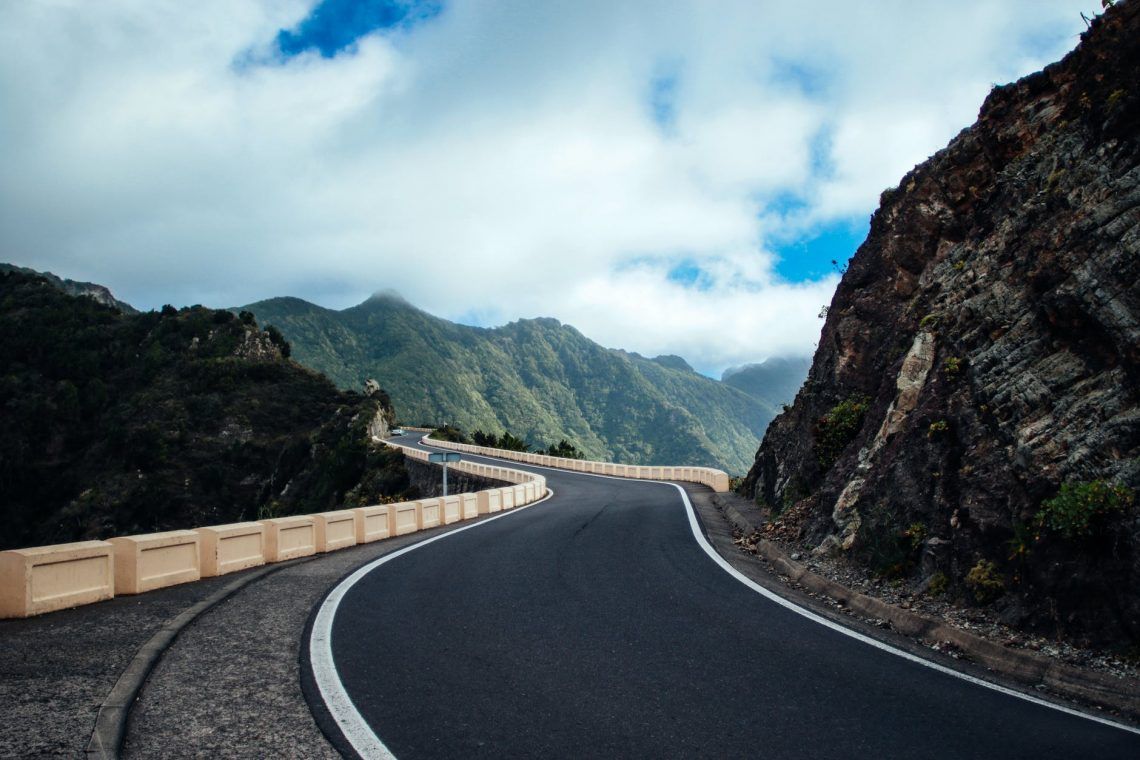 black asphalt road near cliff mountain