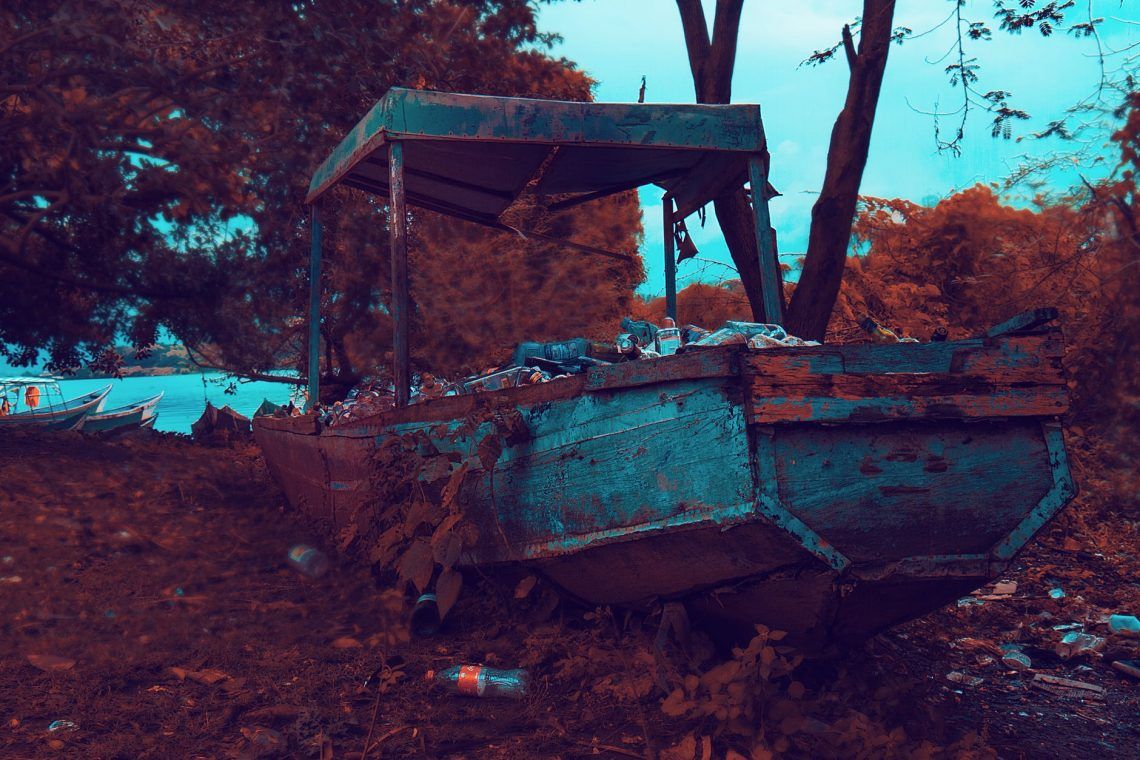rusty brown and gray boat near trees and body of water