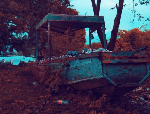 rusty brown and gray boat near trees and body of water
