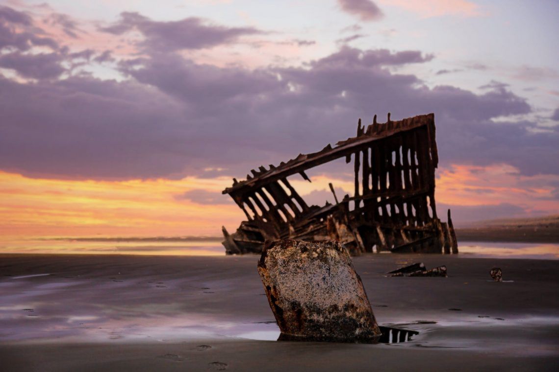 a damaged structure on seashore at dusk