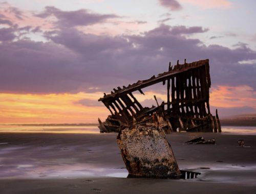 a damaged structure on seashore at dusk