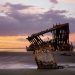 a damaged structure on seashore at dusk