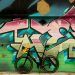 bicycle standing next to a graffiti wall