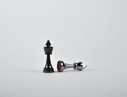 two silver chess pieces on white surface