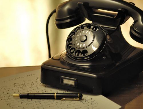 black rotary telephone beside ball pen on white printed paper