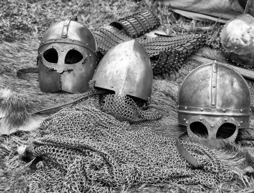 grayscale photography of chainmails and helmets on ground